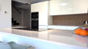 a kitchen with white cabinets and a plate of oranges at ALLONBAY spa & beach house in Villajoyosa +26 photos