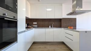 a white kitchen with white cabinets and a sink at ALLONBAY spa & beach house in Villajoyosa