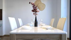 a white table with chairs and a vase with flowers at ALLONBAY spa & beach house in Villajoyosa