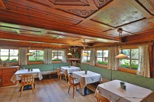 a dining room with tables and chairs and windows at Hotel Garni Hanslerhof " Urlaub am Bauernhof " in Gerlos