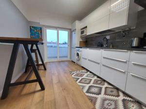 a kitchen with white cabinets and a table at Praia Dona Ana - Bedrooms in shared apartment in Lagos