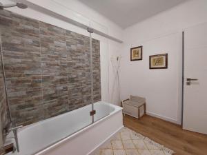 a bathroom with a bathtub and a brick wall at Praia Dona Ana - Bedrooms in shared apartment in Lagos