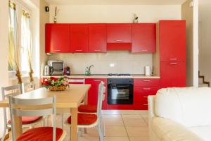 a kitchen with red cabinets and a table and a couch at Apartment Maya - Tremezzina in Tremezzo