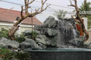a waterfall in a garden in front of a house at Lux Hotel in Luang Prabang