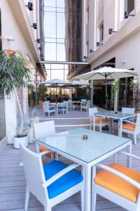 an outdoor patio with tables and chairs and umbrellas at Kyriad Hotel Salalah in Salalah