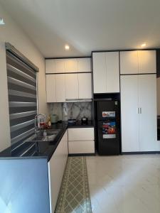 a kitchen with white cabinets and a black refrigerator at Mochi Home in An Dương