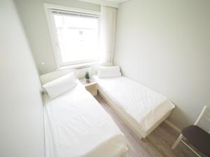 a white room with two beds and a window at App 12-A67 in Westerland
