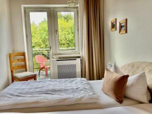 ein Schlafzimmer mit einem Bett, einem Fenster und einem Stuhl in der Unterkunft Hotel Barbara in Warmensteinach