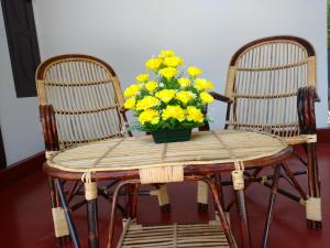 a wooden table with a vase of yellow flowers on it at Marari Das Beach Villa in Mararikulam
