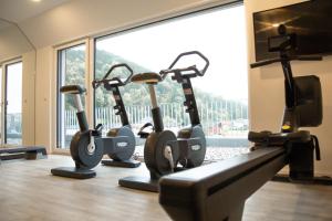 Eine Reihe von Heimtrainern in einem Fitnessstudio mit einem großen Fenster in der Unterkunft Hotel Weiß in Munderfing