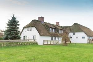 a large white house with a thatched roof at Hansen Hof 1 in Tinnum