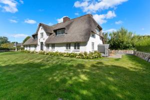 a large white house with a grass yard at Carolinen Hof 1 in Tinnum