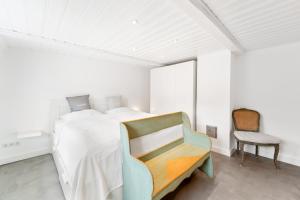 a white bedroom with a bed and a chair at Carolinen Hof 1 in Tinnum