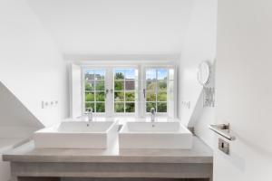 two sinks in a white bathroom with a window at Carolinen Hof 1 in Tinnum +40 photos