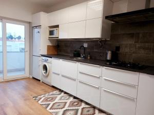 a kitchen with white cabinets and a washing machine at Praia Dona Ana - Bedrooms in shared apartment in Lagos