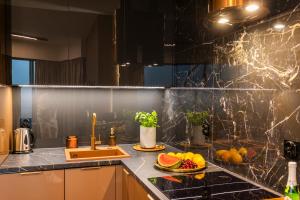 a kitchen with a sink and fruits on a counter at Kaleo apartments - Hanza Tower in Szczecin