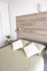 a bed with two pillows and a wooden headboard at studio tout équipé, calme avec terrasse et parking in Audincourt