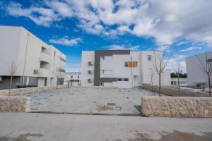 a view of two white buildings in a parking lot at Apartments Olive Gardens 2 in Novalja