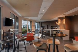 a restaurant with tables and chairs and a tv at Spark by Hilton Lyon Eurexpo in Genas