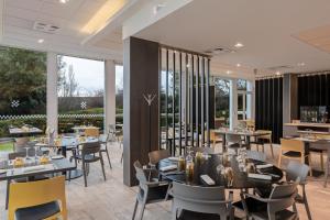a restaurant with tables and chairs and large windows at Spark by Hilton Lyon Eurexpo in Genas