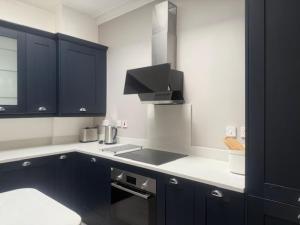 a kitchen with black cabinets and a stove top oven at Murrayfield Gem in Edinburgh