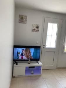 a living room with a flat screen tv on a dresser at Petite maison de village in Ancerville