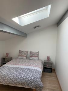 a bedroom with a bed and a skylight at Petite maison de village in Ancerville