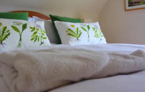 Cama blanca con almohadas verdes y blancas y manta en Bramley Cottage, en Ottery St Mary