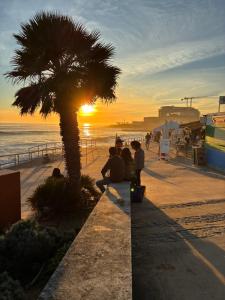 a group of people sitting under a palm tree on the beach at MAR VERDE - Parede-Cascais in Parede