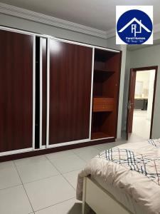 a bedroom with a bed and a large wooden cabinet at FOREL RESIDENCE Jc in Accra