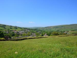 a field of green grass with a town in the distance at 2 Bed in High Peak oc-57871 in Hayfield