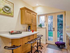 a kitchen with wooden cabinets and bar stools at 2 Bed in Coleford oc-78181 in Symonds Yat +13 photos