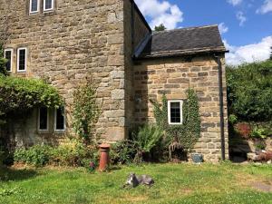 a cat laying in the grass in front of a stone house at 3 Bed in Belper oc-85797 in Crich +21 photos