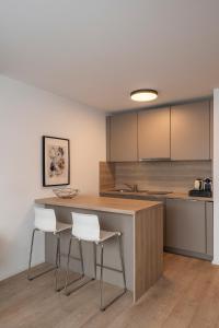 a kitchen with a counter and two stools at Aparthotel Cosy in Stuttgart