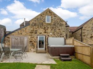 a stone house with a hot tub in the yard at 3 Bed in Matlock oc-78717 in Crich