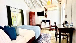 a bedroom with a bed and a desk and a table at Ecoya Riverside Resort in Balapitiya