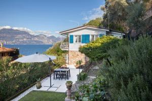 a house with an umbrella and a table and chairs at Il Nido in Brenzone sul Garda