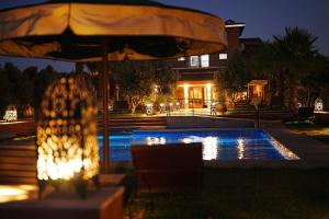 a table with an umbrella next to a swimming pool at night at Maison d'Hôtes Errafiqi in Safi