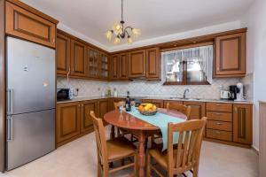 a kitchen with wooden cabinets and a table with a bowl of fruit at Villa Kiotari by Villa Plus in Kiotari