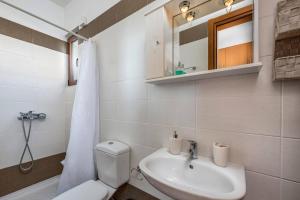 a bathroom with a sink and a toilet and a mirror at Villa Kiotari by Villa Plus in Kiotari +35 photos