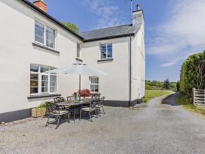 a table with chairs and an umbrella in front of a house at 6 Bed in Okehampton oc-estra in Okehampton