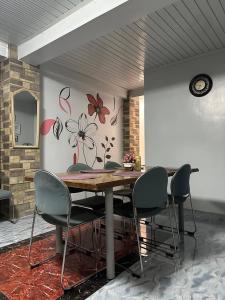 a dining room table with chairs and a wall with flowers at Koenigs Lodging House in Bocaue