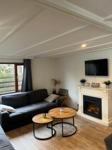 a living room with a black couch and a fireplace at Hottub Forest Chalet op de Veluwe! in Putten