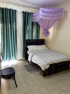 a bedroom with a bed with a purple curtain at Next Level in Gulu