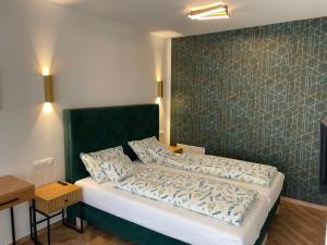 a bedroom with a bed with a green headboard at Jancsó Apartman in Dunaföldvár