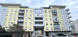 a tall yellow building with cars parked in front of it at Cozy City Studio in Podgorica, Blok 9 in Podgorica +4 photos