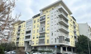 a yellow building with cars parked in front of it at Cozy City Studio in Podgorica, Blok 9 in Podgorica