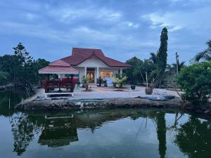 a house sitting next to a body of water at Baan Farang in Samut Songkhram