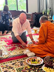 two monks sitting on the floor in a room with food at Baan Farang in Samut Songkhram