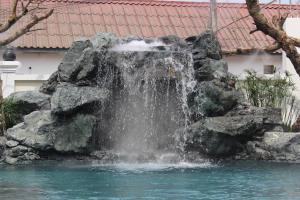 a waterfall in the middle of a pool of water at Lux Hotel in Luang Prabang